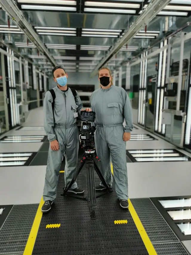 Camera crew in protective suits in an automotive paint shop
